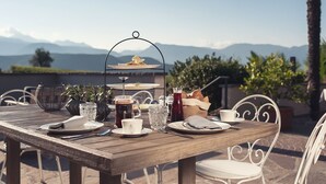 A wooden table set for breakfast with a view of mountains in the background. - Das Wanda (Caldaro Sulla Strada del Vino)