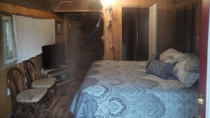 Habitació acollidora amb llit, cadira de balançà, televisió i una taula petita.
