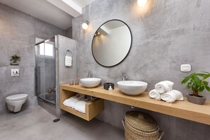 Ein modernes Badezimmer mit einem großen Spiegel, zwei Waschbecken, einer Dusche und einem Handtuchhalter.