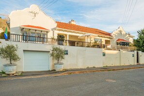 A two-story house with a red-tiled roof, a white exterior, and a garage door.
