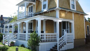 Uma casa de dois andares com varanda em volta, varanda no andar superior e chaminé.