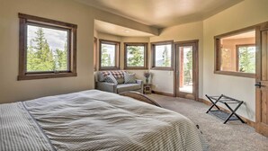 A bedroom with a large bed, a sofa, and multiple windows offering views of trees. - 26-0111 Fairplay Home w/ Hot Tub & Mountain Views! (Fairplay)