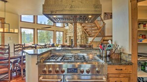 A kitchen with a large island, stainless steel appliances, and a stone accent wall. - 26-0111 Fairplay Home w/ Hot Tub & Mountain Views! (Fairplay)
