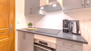 A modern kitchen with grey cabinets, a wooden door, a black countertop, a coffee maker, and a kettle. - Perfect large beautiful apartment for Families with Children in Centre of Nice (Nice)
