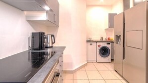 A compact kitchen with a black countertop, a coffee maker, a washing machine, and a refrigerator. - Perfect large beautiful apartment for Families with Children in Centre of Nice (Nice)