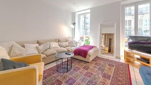 A living room with a sofa, a coffee table, a TV, and a patterned rug. - Perfect large beautiful apartment for Families with Children in Centre of Nice (Nice)