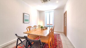 A dining area with a wooden table and chairs, a red patterned rug, and a large window with a view. - Perfect large beautiful apartment for Families with Children in Centre of Nice (Nice)