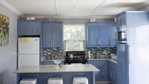 Une cuisine avec des armoires bleues, un réfrigérateur blanc, une cuisinière et un four à micro-ondes.