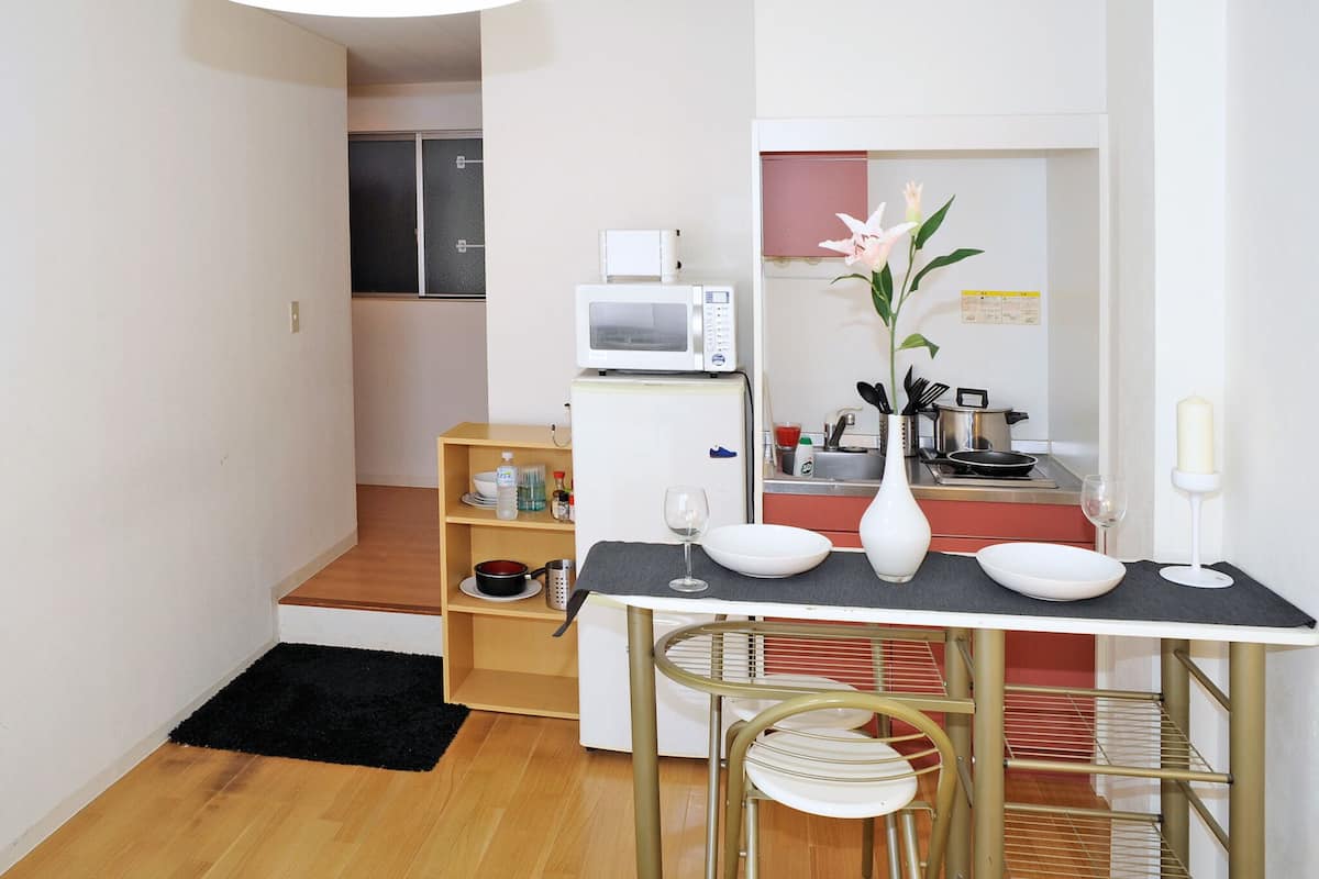 A compact kitchen with a microwave, a small refrigerator, and a dining area with a table and chairs.
