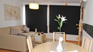 Ein modernes Wohnzimmer mit einem beigen Sofa, einem runden Holzesstisch und einer weißen Vase mit Blumen.