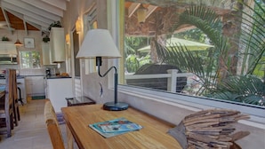 Een keuken met een houten tafel, een lamp en een raam met uitzicht op palmbomen.