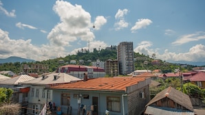 A town with a cable car, buildings, and a mountainous backdrop. - Hotel Cosmos (Batumi)
