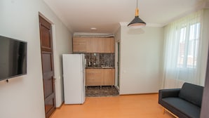 A compact living space with a kitchenette, a sofa, and a TV. - Hotel Cosmos (Batumi)
