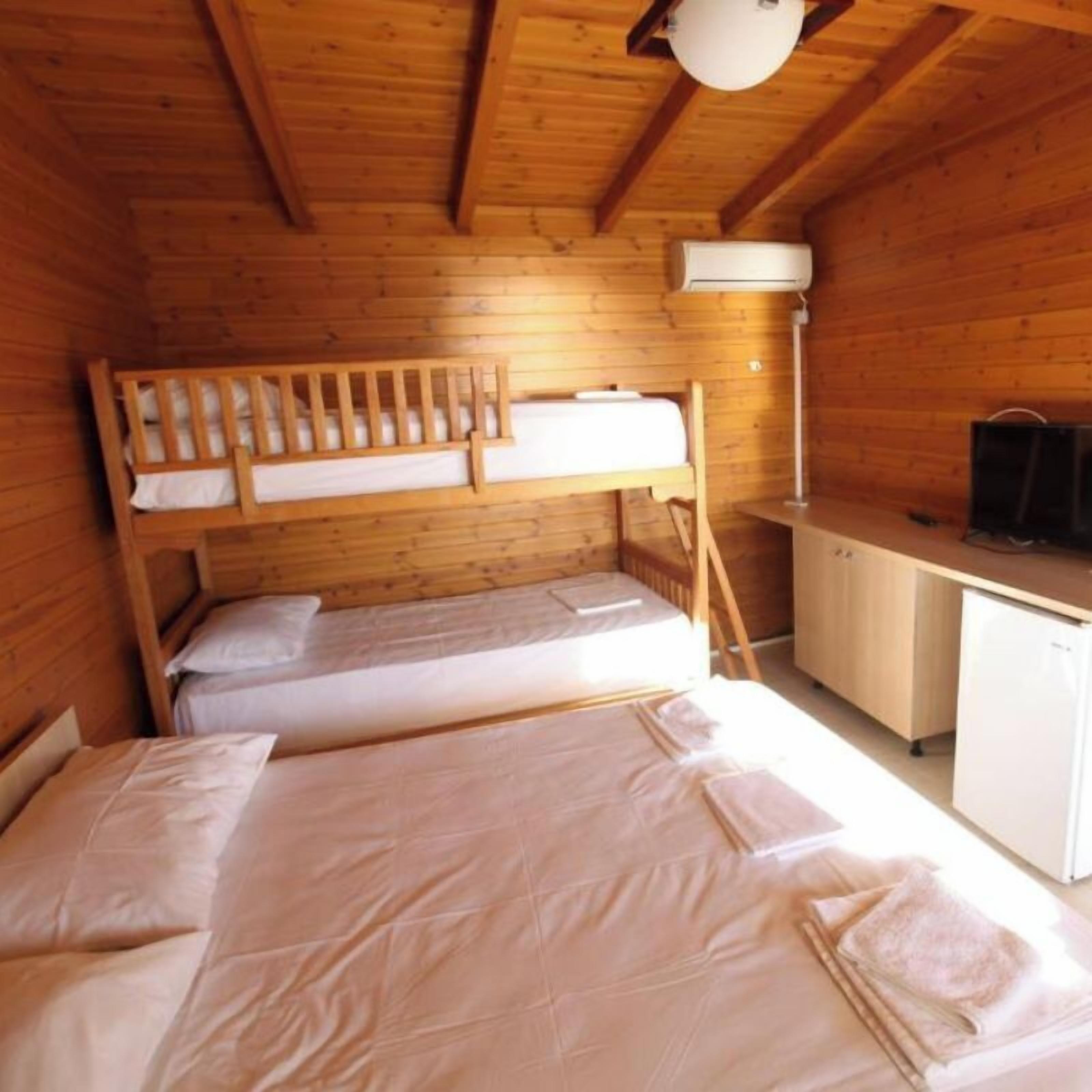 A wooden cabin with bunk beds, a desk, and a television.