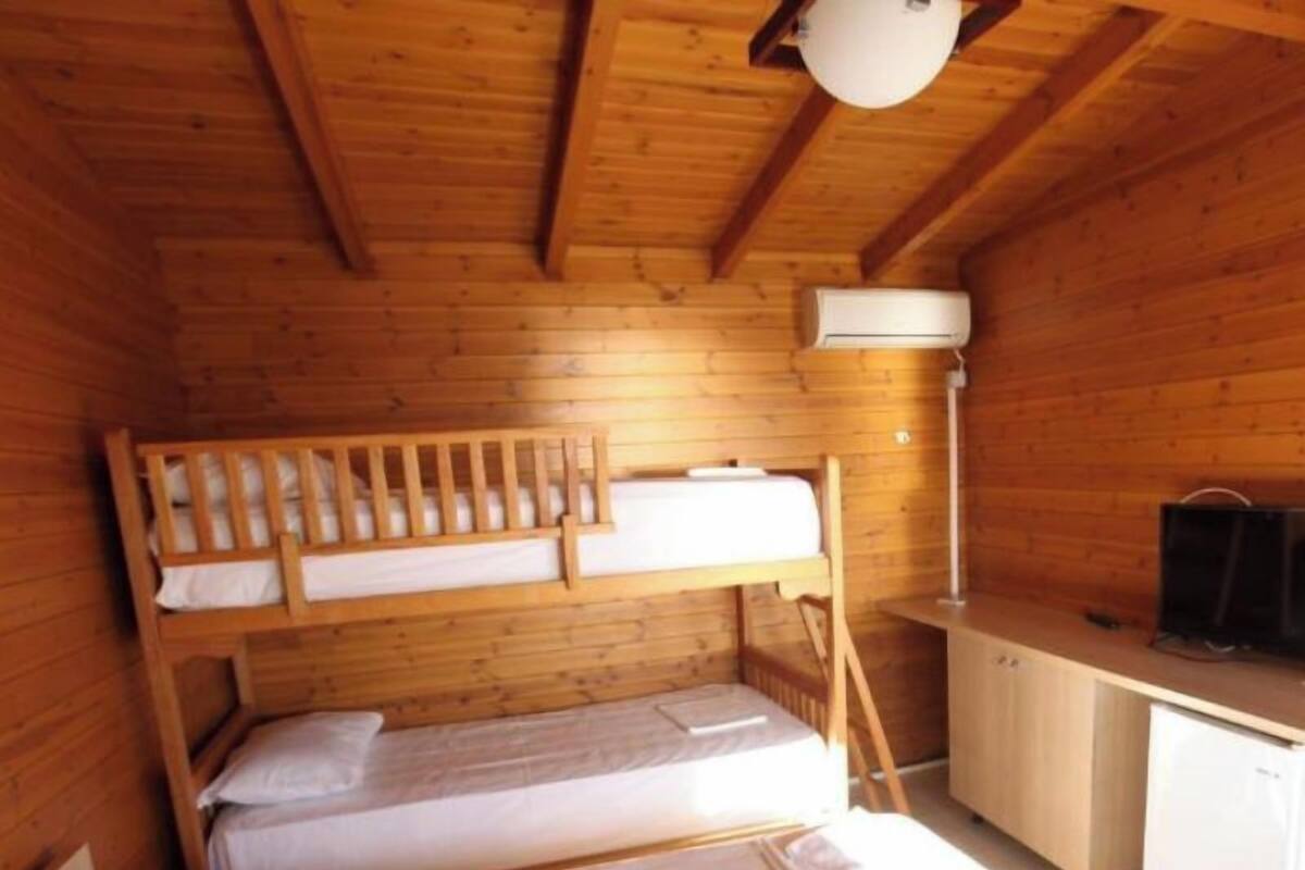 A wooden cabin with bunk beds, a desk, and a television.