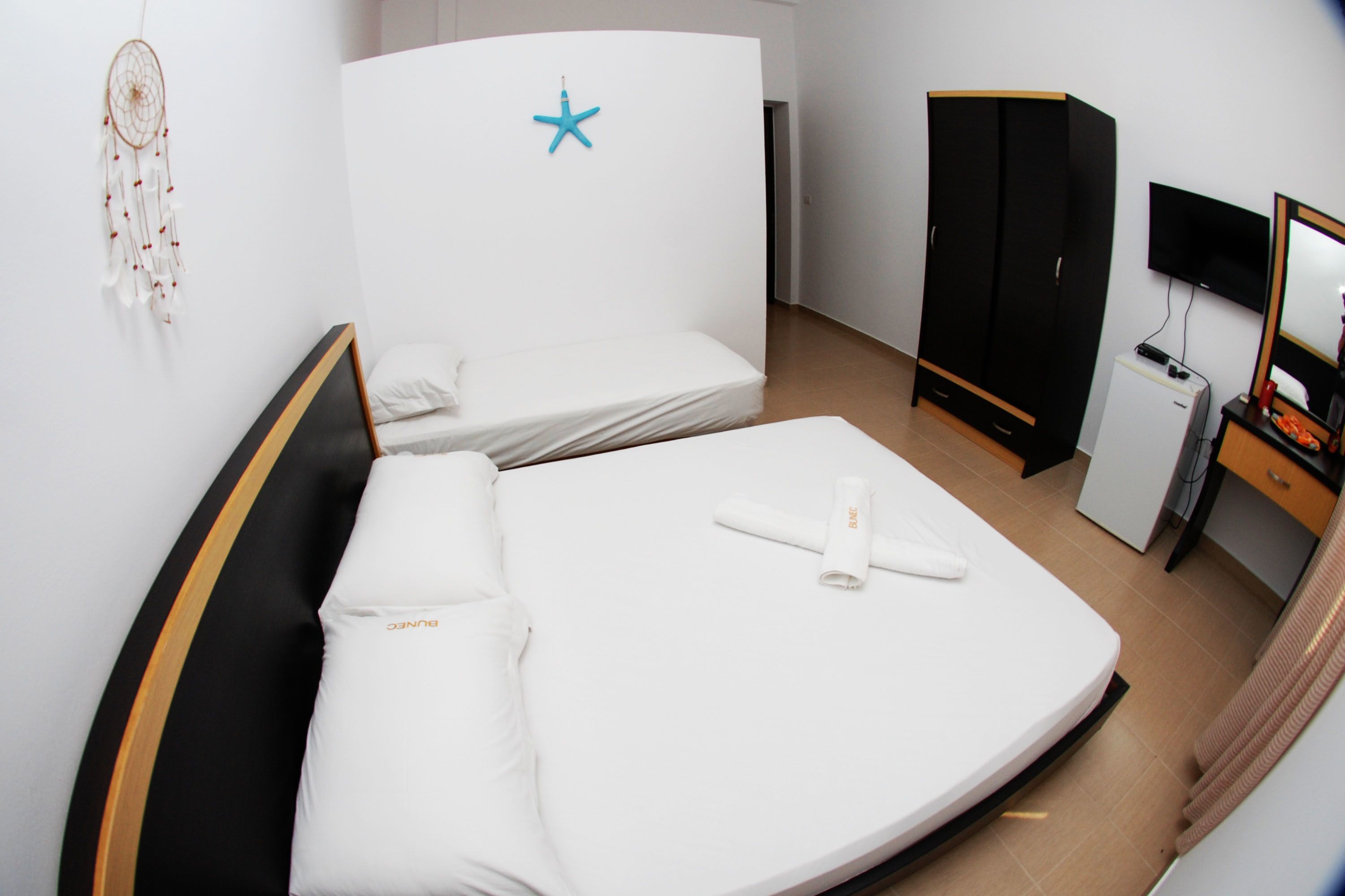 Una habitación de hotel con cama, armario, escritorio con computadora y televisor.