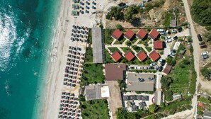 An aerial view of a coastal resort with beachside accommodations, a parking area, and a road leading to the beach. - Bunec Beach Resort (Lukovë)