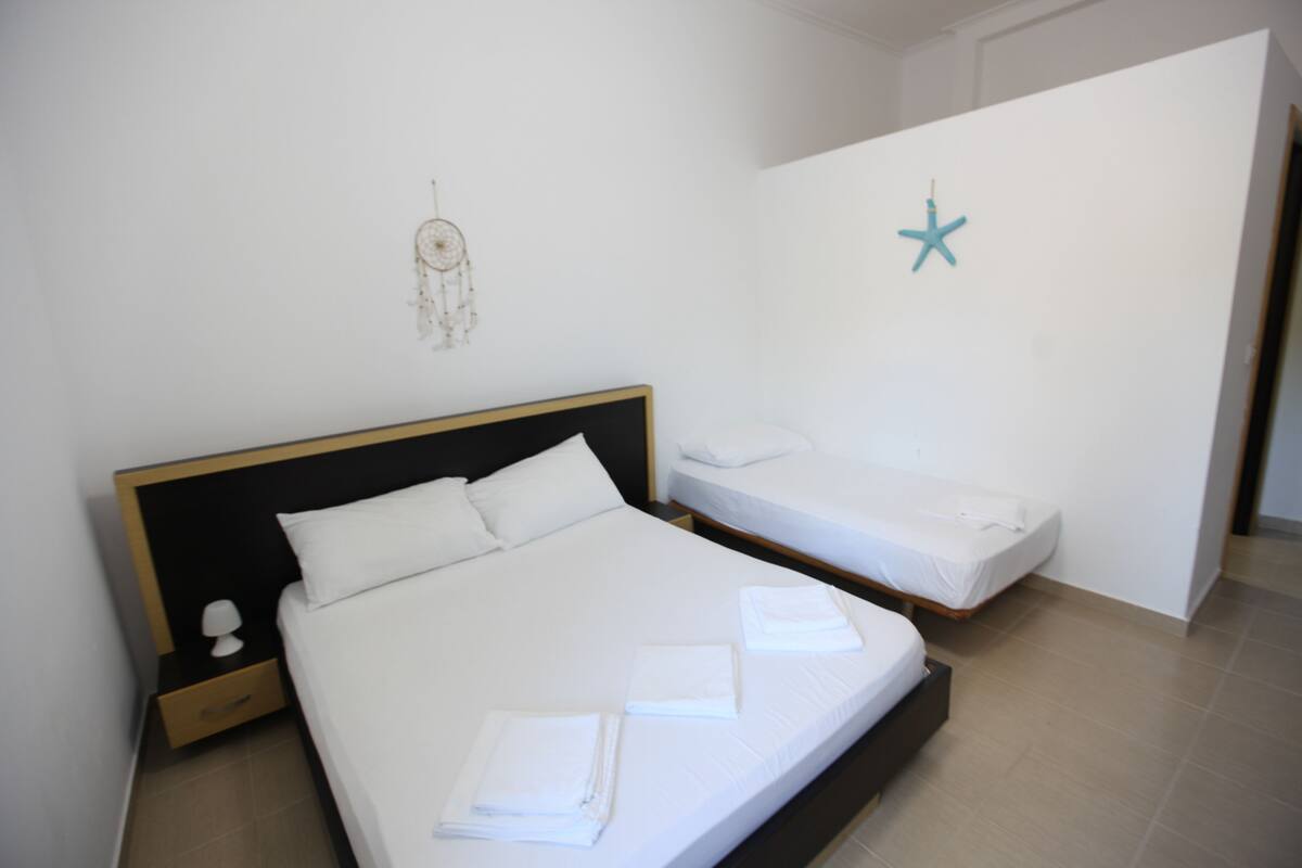 A hotel room with a large bed, a smaller bed, a nightstand, and a wall decoration.