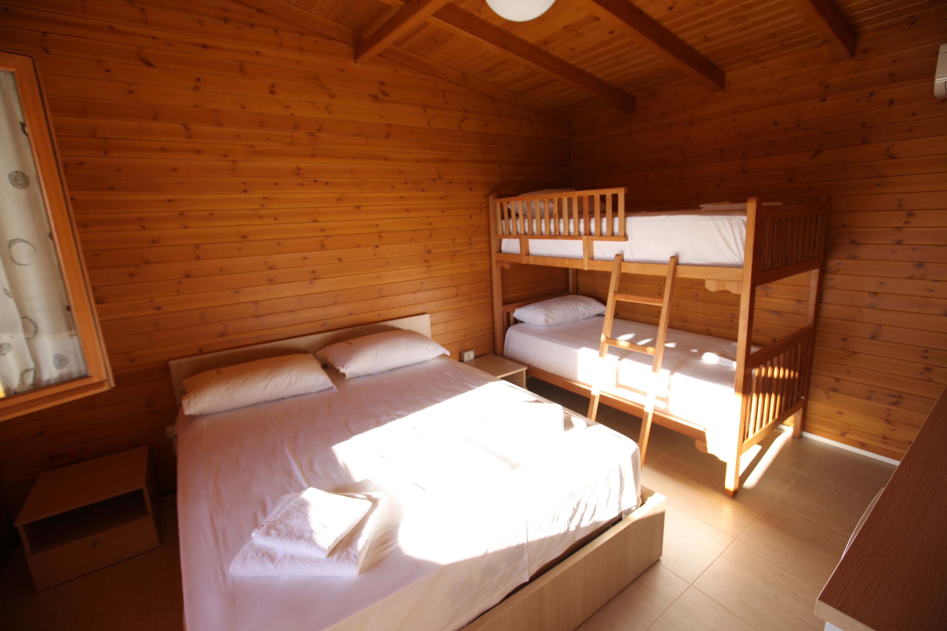 Une chambre dans un chalet en bois, avec des lits superposés, un lit simple et une petite table.