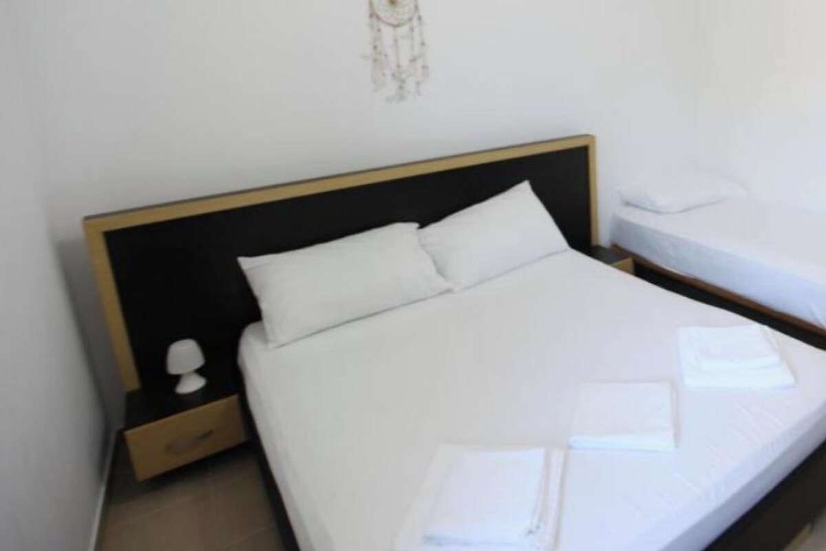 Habitación de hotel con una cama individual, una mesita de noche, una decoración en la pared y una cama bien hecha con toallas.