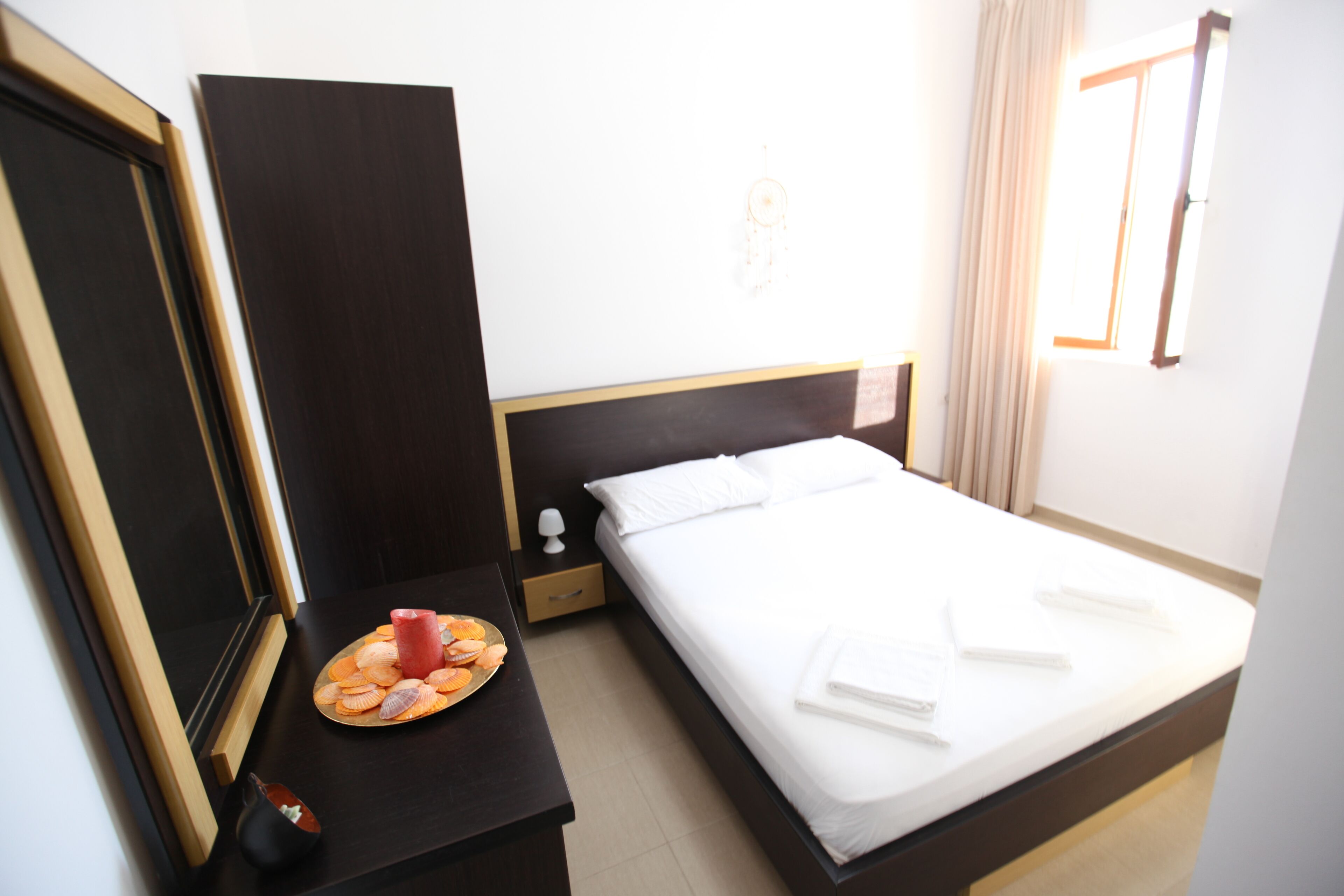 A hotel room with a bed, bedside table, and a wall-mounted dreamcatcher.