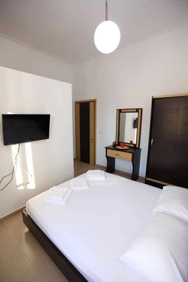 A hotel room with a bed, a flat-screen TV mounted on the wall, a dresser, a mirror, and a wardrobe. - Bunec Beach Resort (Lukovë)