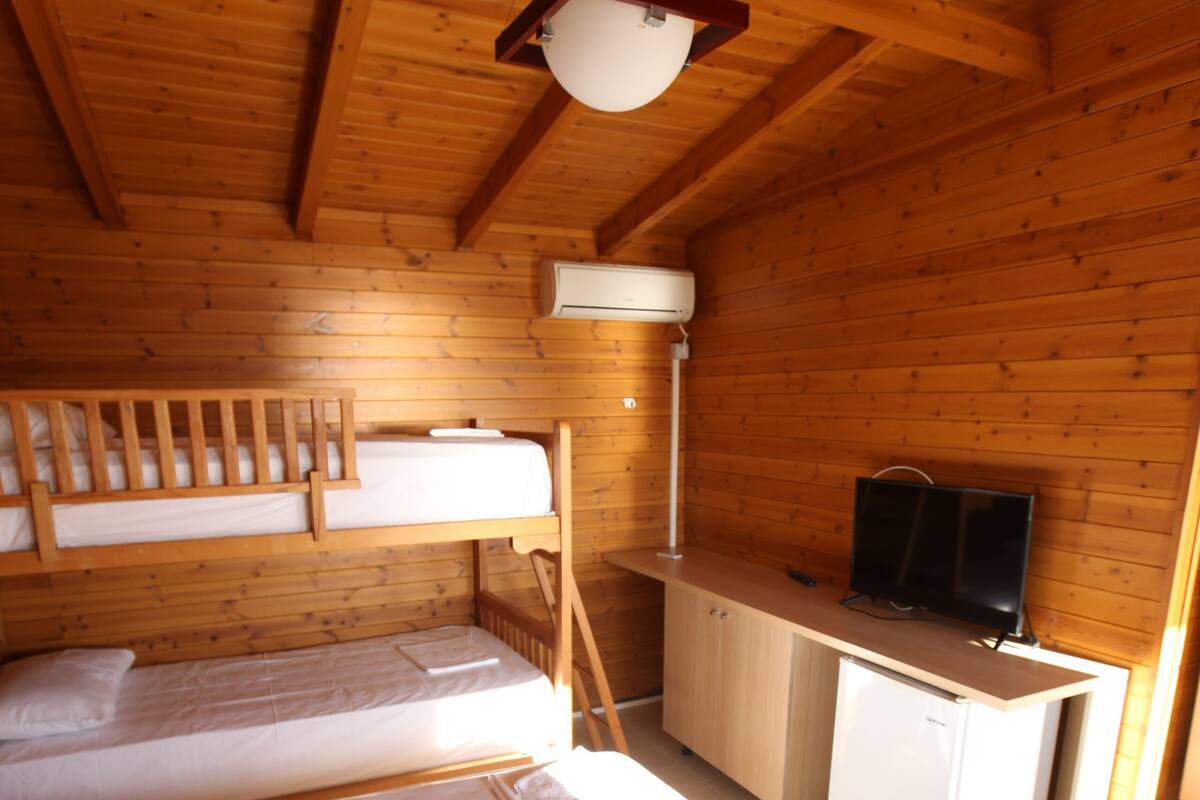 A cabin-style room with two bunk beds, a desk, and a television.