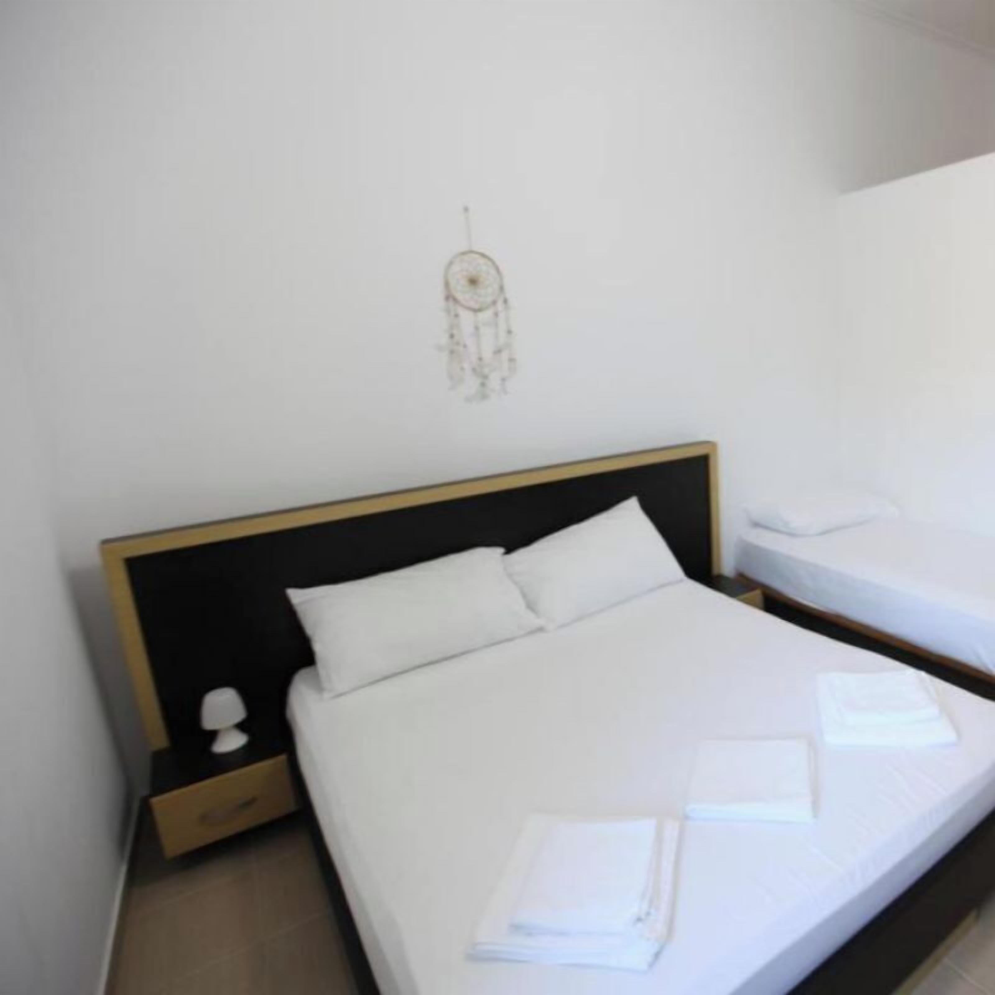 A hotel room with a single bed, a nightstand, a wall decoration, and a neatly made bed with towels.