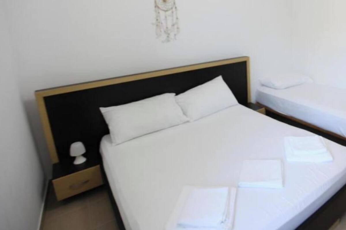 A hotel room with a single bed, a nightstand, a wall decoration, and a neatly made bed with towels.