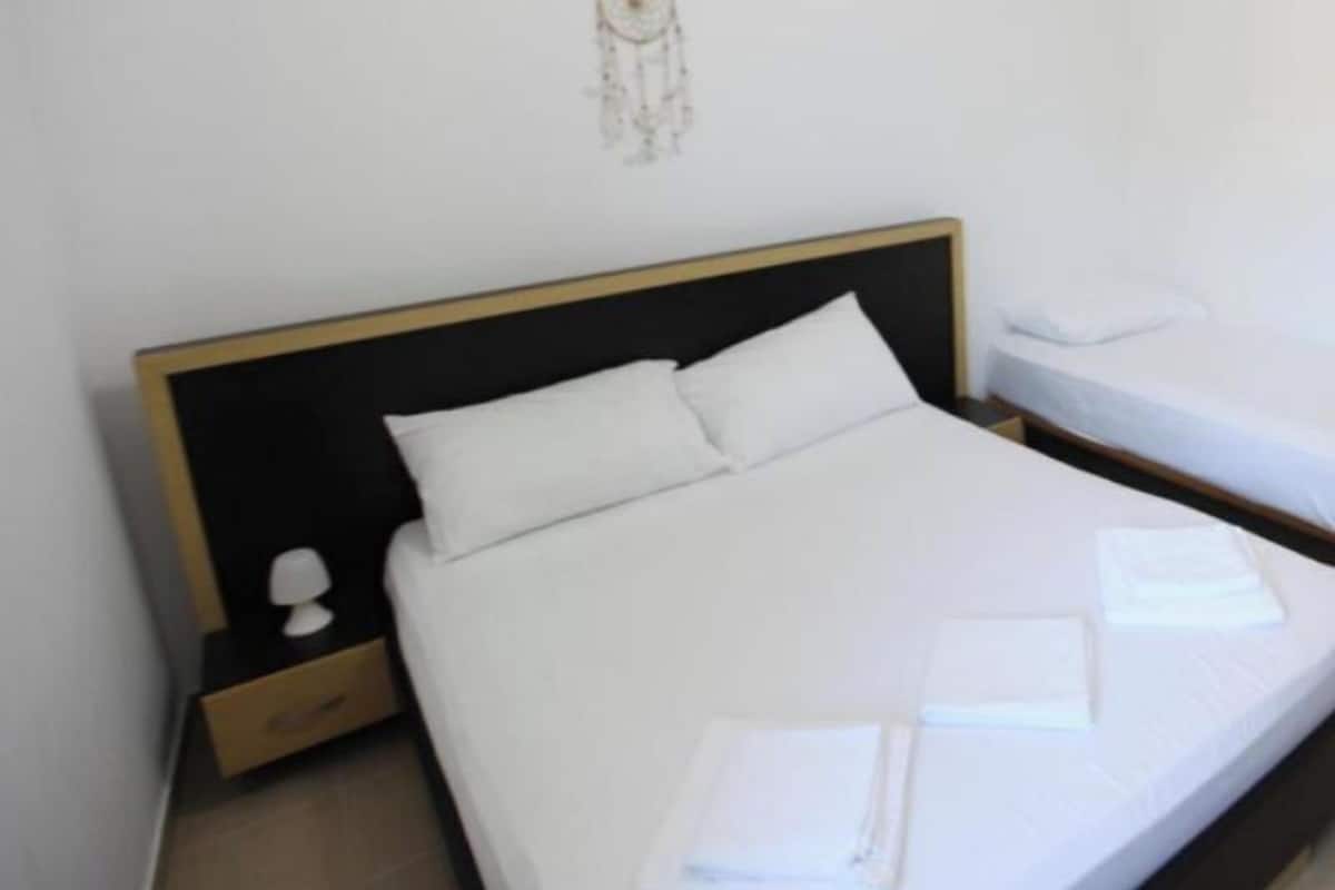 A hotel room with a single bed, a nightstand, a wall decoration, and a neatly made bed with towels.