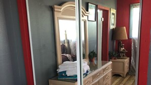 Quarto com um espelho grande, piso de madeira e um penteado com toalhas dobradas.