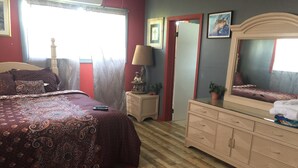 Quarto com cama grande, penteadeira, espelho e mesa de cabeceira.