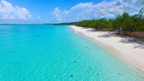 Uma praia com águas turquesa cristalinas e uma orla arenosa.