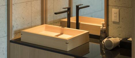Un baño moderno con tocador de madera, grifo negro y secador de pelo en la encimera.