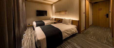 A hotel room with two beds, a flat-screen TV mounted on the wall, and a wooden door.
