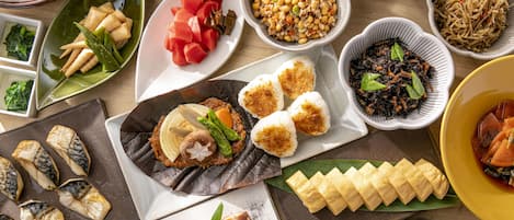 Variedad de platos, incluyendo sushi, sashimi y otras cocinas asiáticas, dispuestos sobre una mesa de madera.
