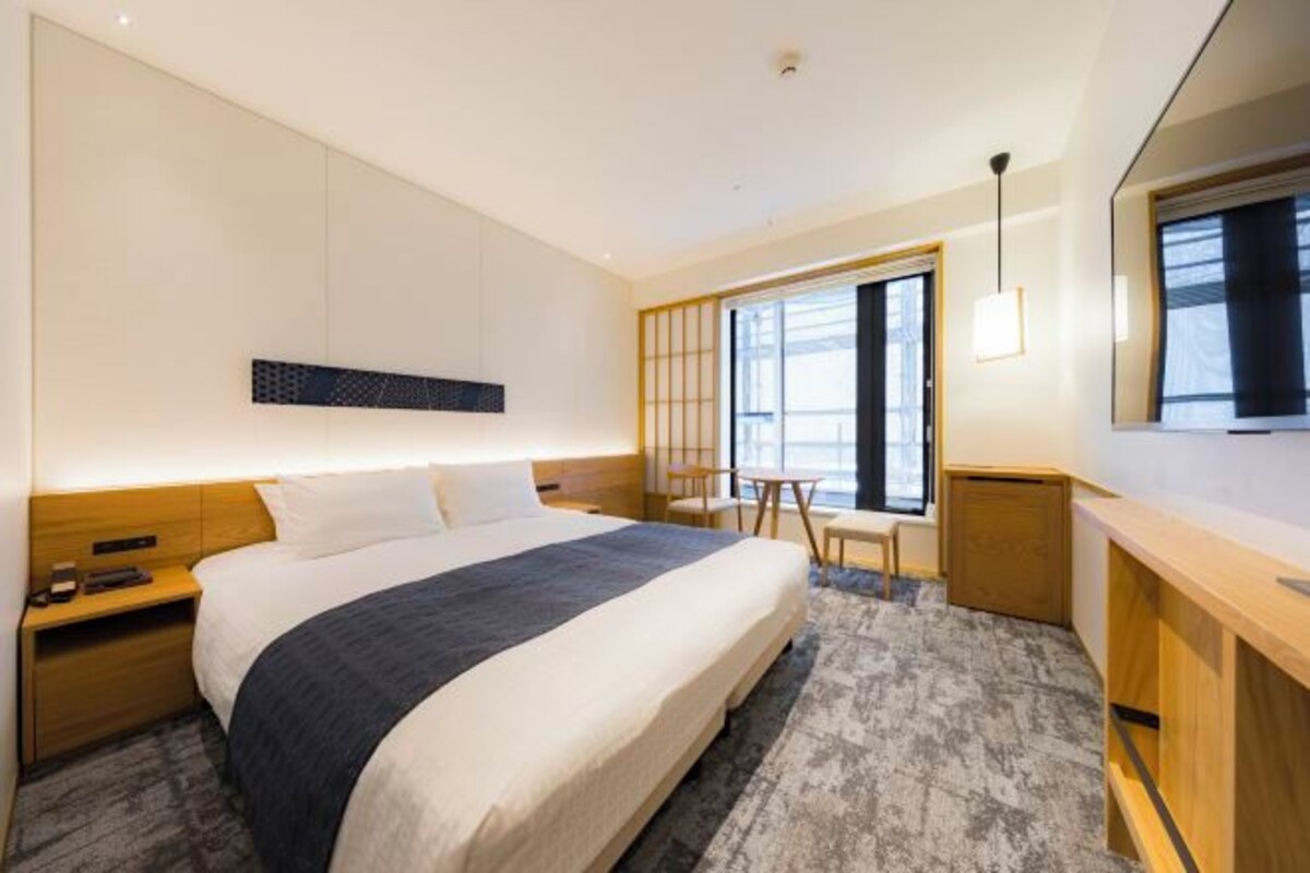 Une chambre d’hôtel moderne, dotée d’un grand lit, d’un bureau et d’une chaise.
