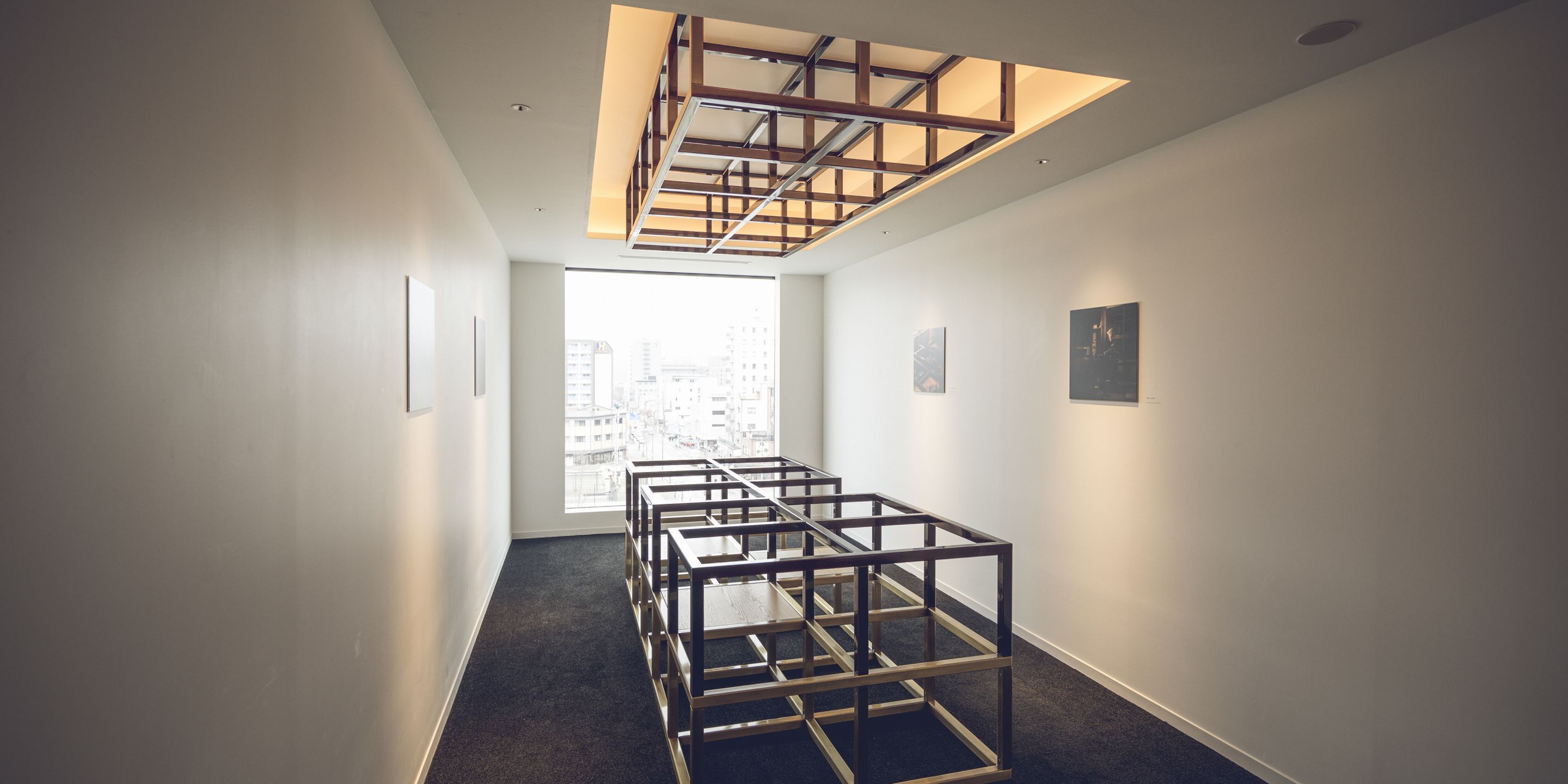 A hallway with a modern, minimalist design, featuring a geometric light fixture and framed artwork on the walls.