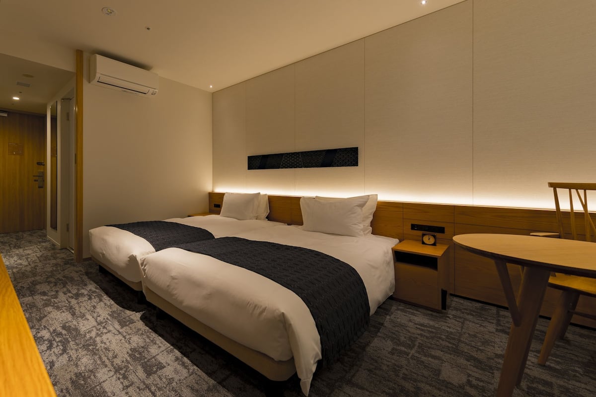 A hotel room with a large bed, bedside tables, a desk, and a chair.