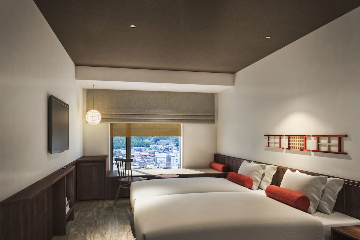 A modern hotel room with a large bed, a desk, and a view of a cityscape.