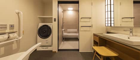 Ein kleines Badezimmer mit Waschmaschine, Waschbecken und Spiegel.