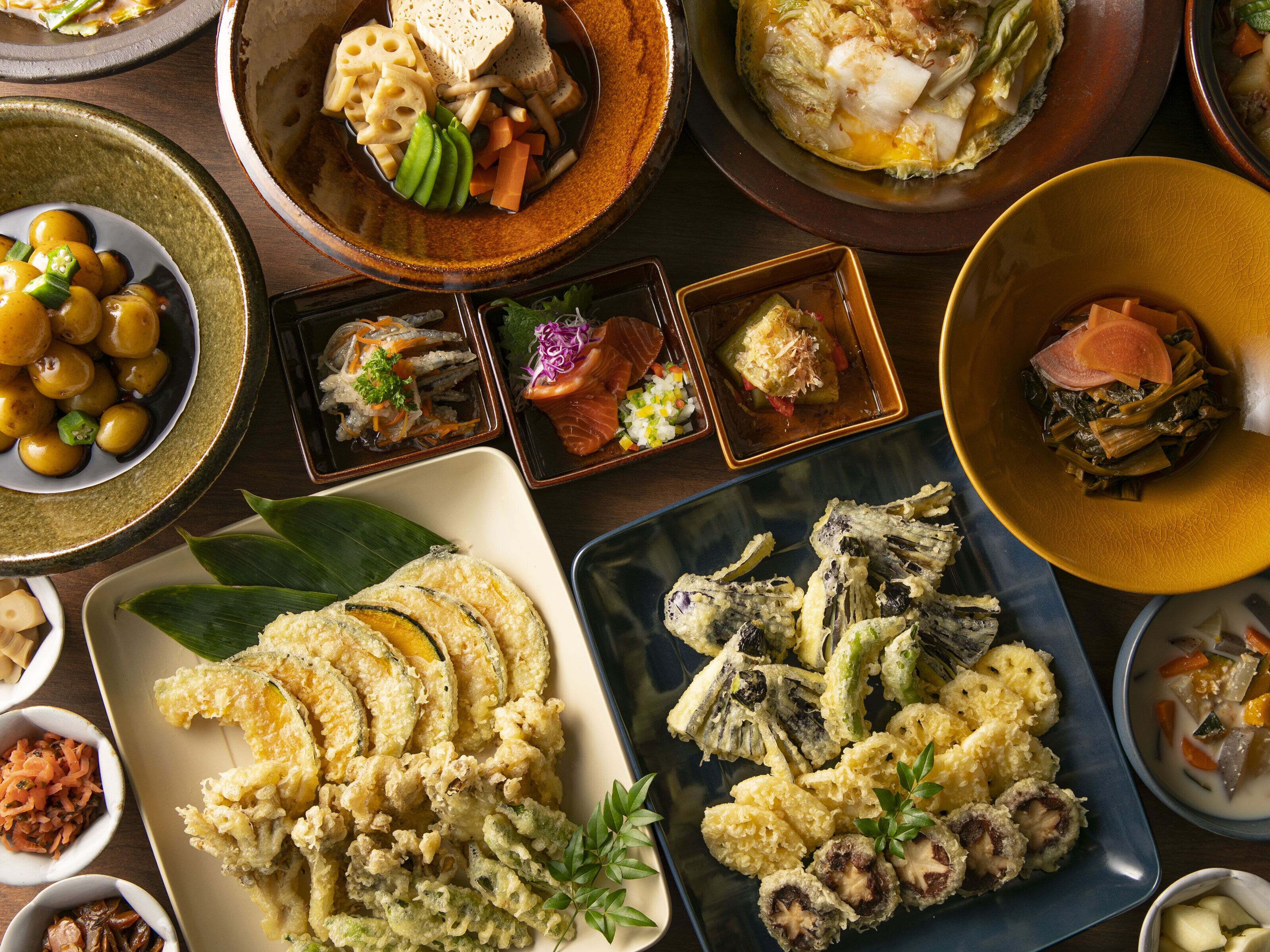 Diverse gerechten, waaronder tempura, sashimi en een schaal groenten.