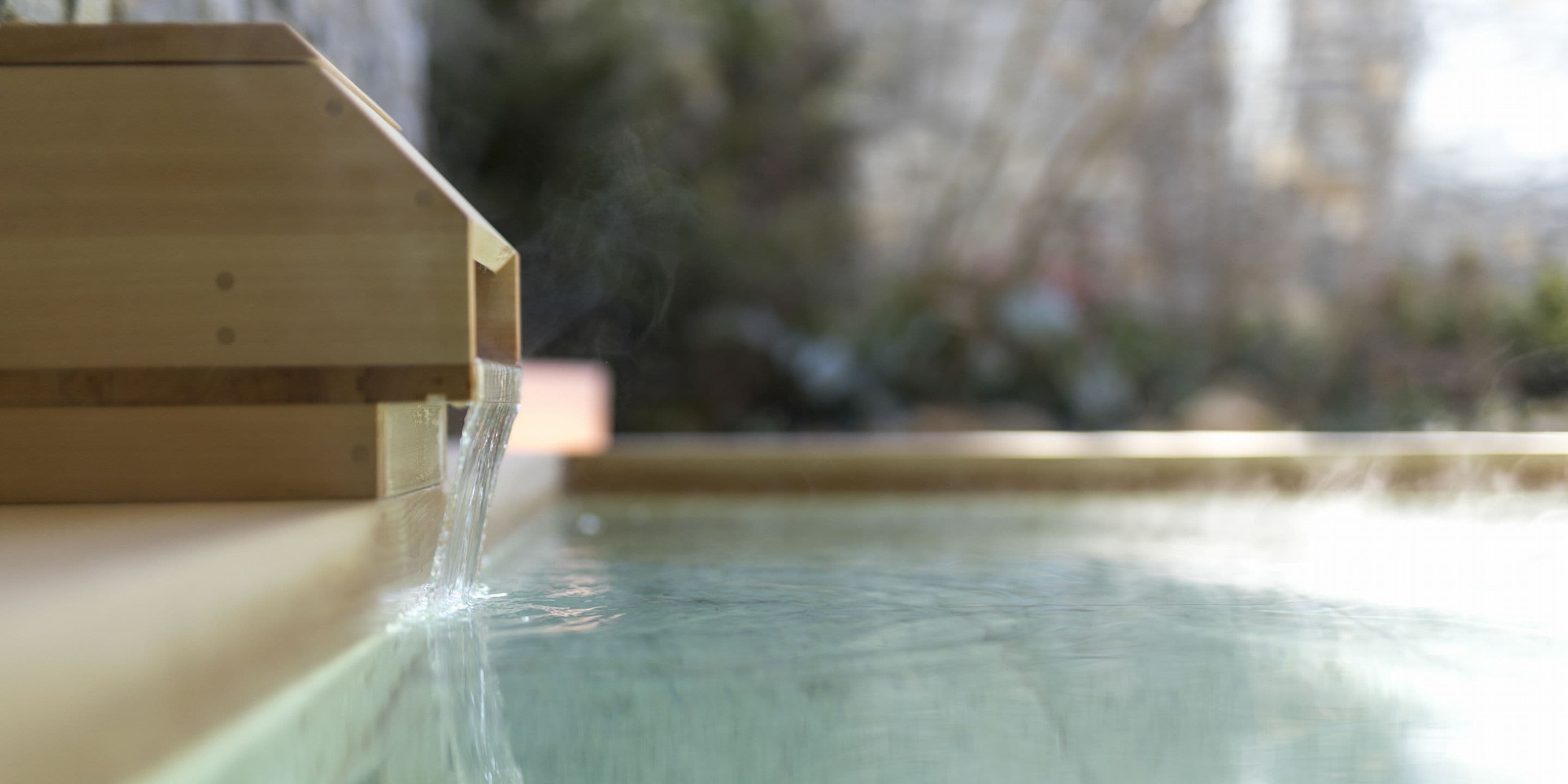 A wooden structure with water flowing from it into a pool.