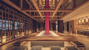 Un hall d’entrée spacieux doté d’un plancher en bois, d’une colonne centrale et d’un espace détente avec des bancs.