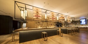 A modern bar area with wooden shelves, a central counter, and bar stools.
