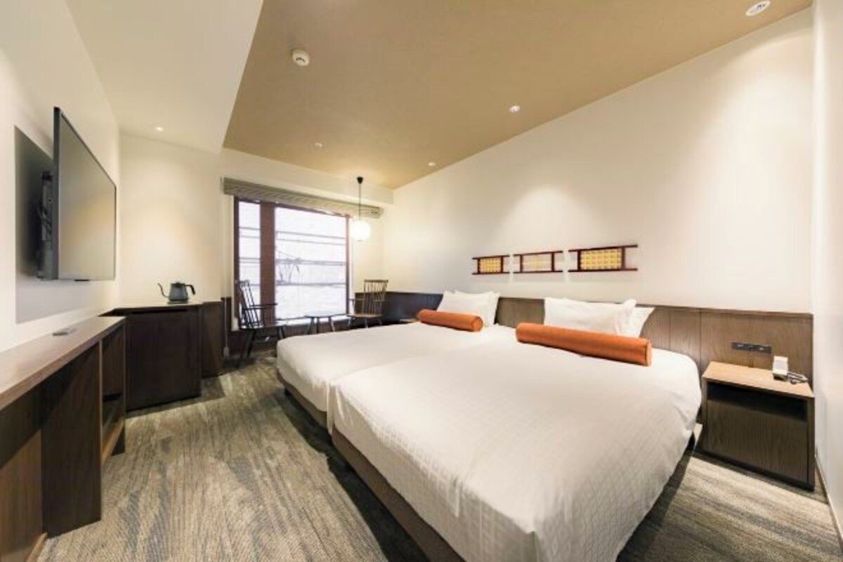 Une chambre d’hôtel avec un grand lit, un bureau, une chaise, une télévision et une fenêtre donnant sur un beau paysage.