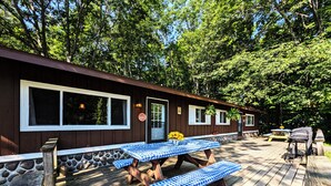 A wooden deck with picnic tables and benches, surrounded by trees. - Amenities & Resort Access Included, Cabin 7 (Phelps)