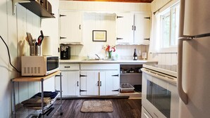 A compact kitchen with white cabinets, a microwave, a coffee maker, and a refrigerator. - Amenities & Resort Access Included, Cabin 7 (Phelps)