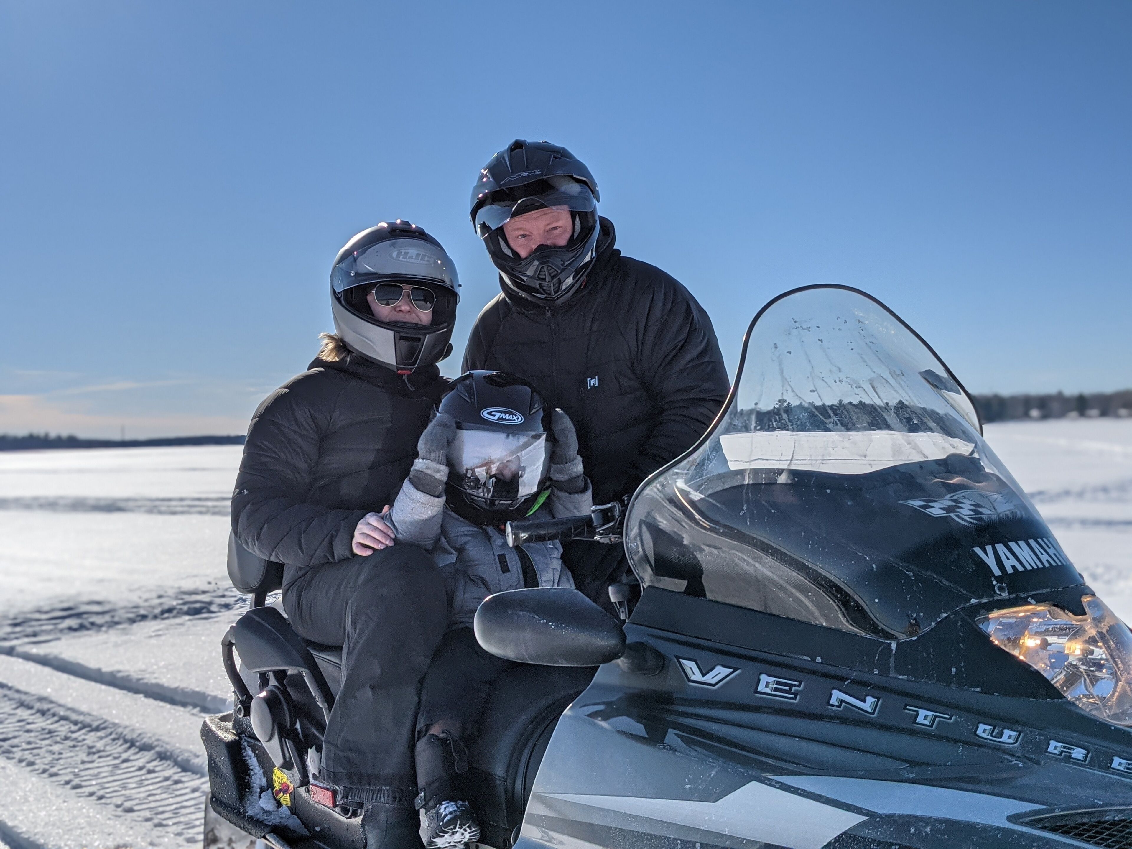 Two people on a snowmobile with a clear sky in the background.