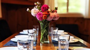 A dining table set with plates, glasses, and a vase of flowers. - Premium Amenities Included! Cabin 9 - POV Resort (Phelps)